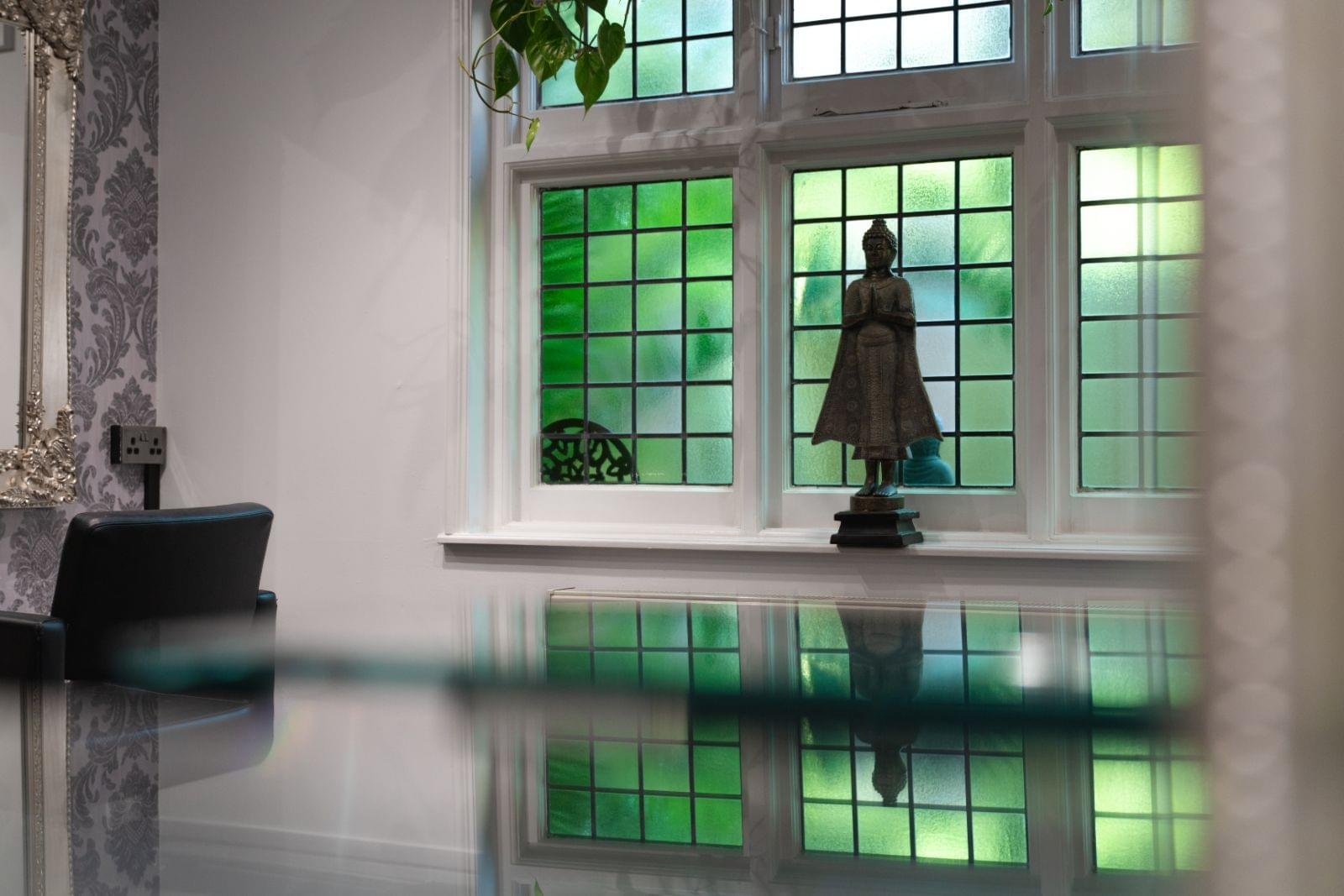 Buddha statue silhouetted in Serenity's green leaded windows