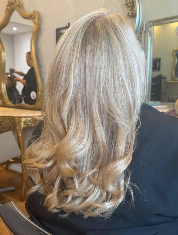 Long platinum blonde hair with soft curls, styled in the salon